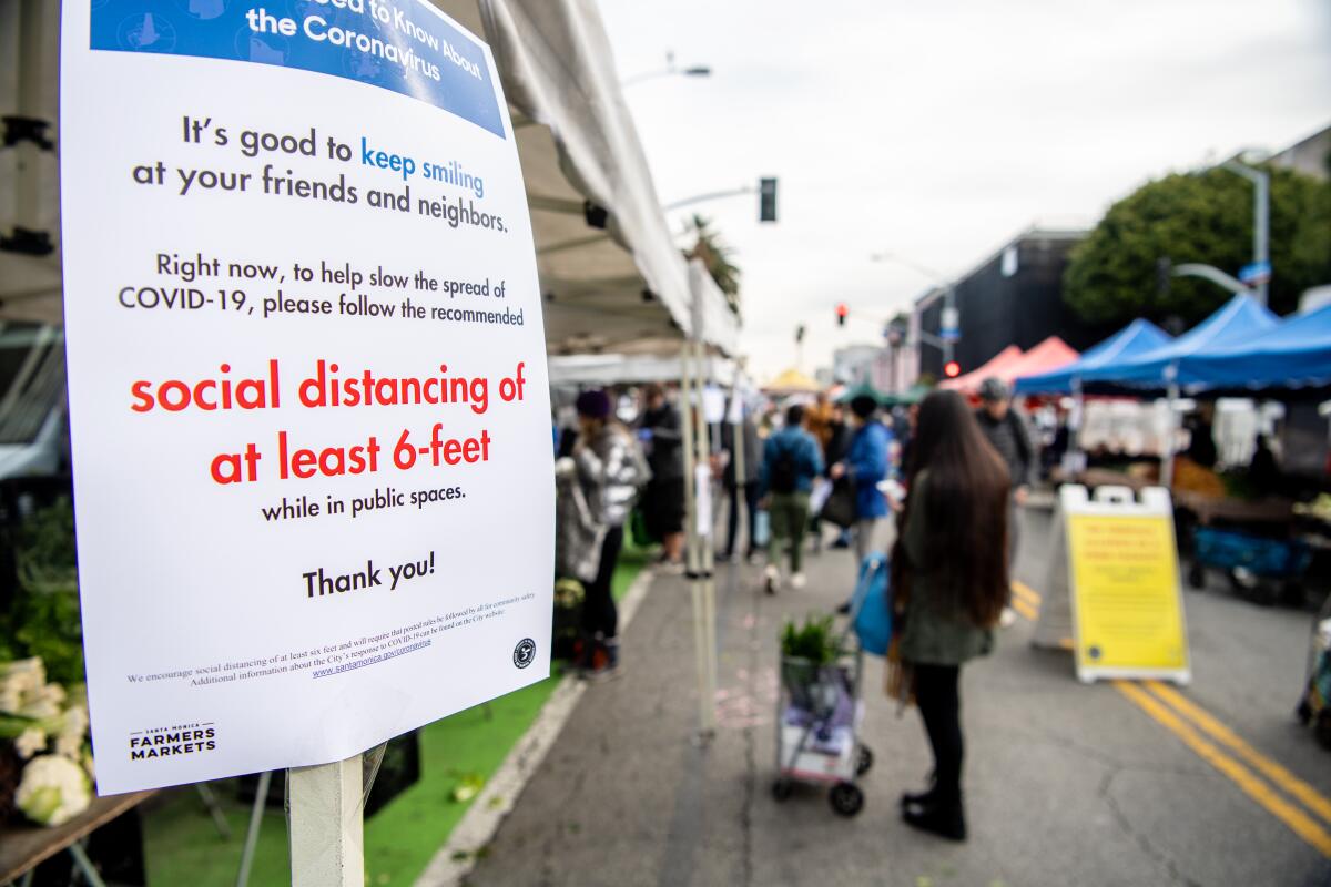 Posted signs ask customers to maintain social distancing at the Santa Monica Farmers Market.