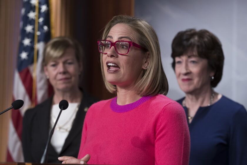 Sen. Kyrsten Sinema, D-Ariz., flanked by Sen. Tammy Baldwin, D-Wis., left, and Sen. Susan Collins, R-Maine, speaks to reporters following Senate passage of the Respect for Marriage Act, at the Capitol in Washington, Tuesday, Nov. 29, 2022. (AP Photo/J. Scott Applewhite)