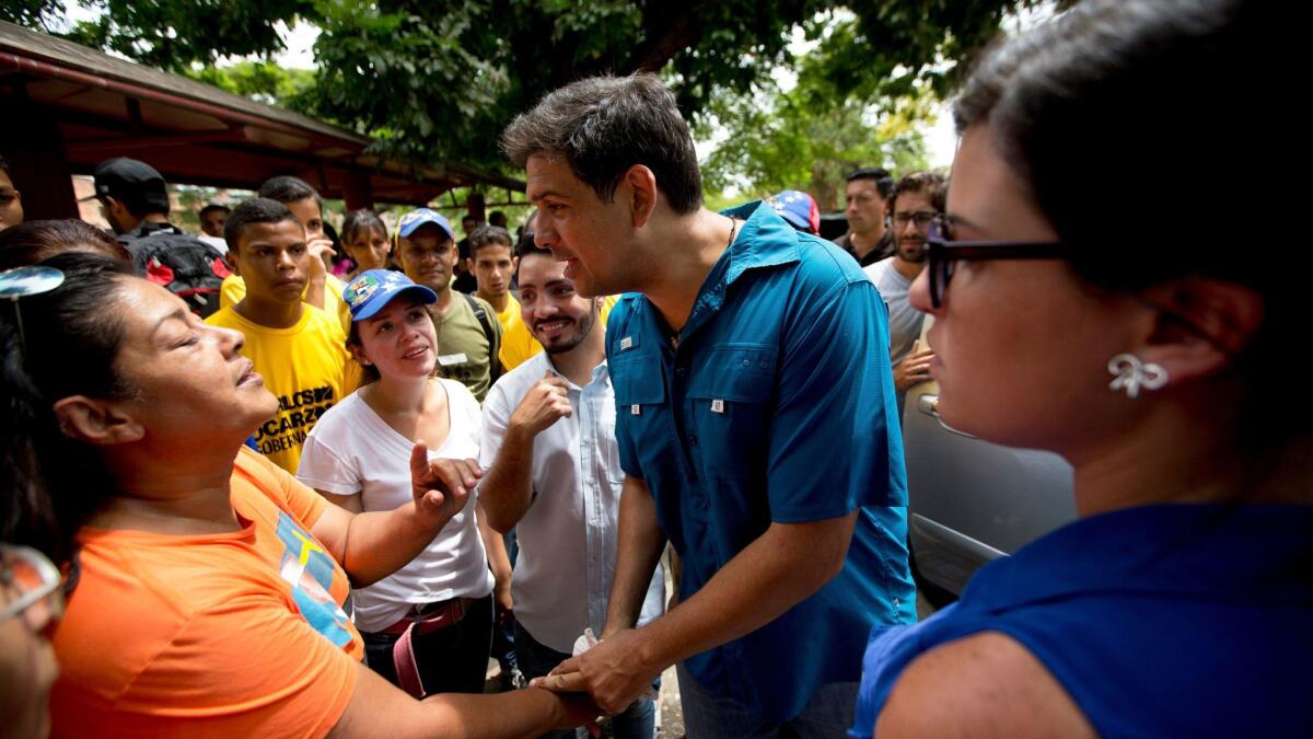 Opposition candidate Carlos Ocariz, who is running for governor of Miranda state, speaks with a woman as he campaigns in Guarenas, on the outskirts of Caracas, Venezuela.