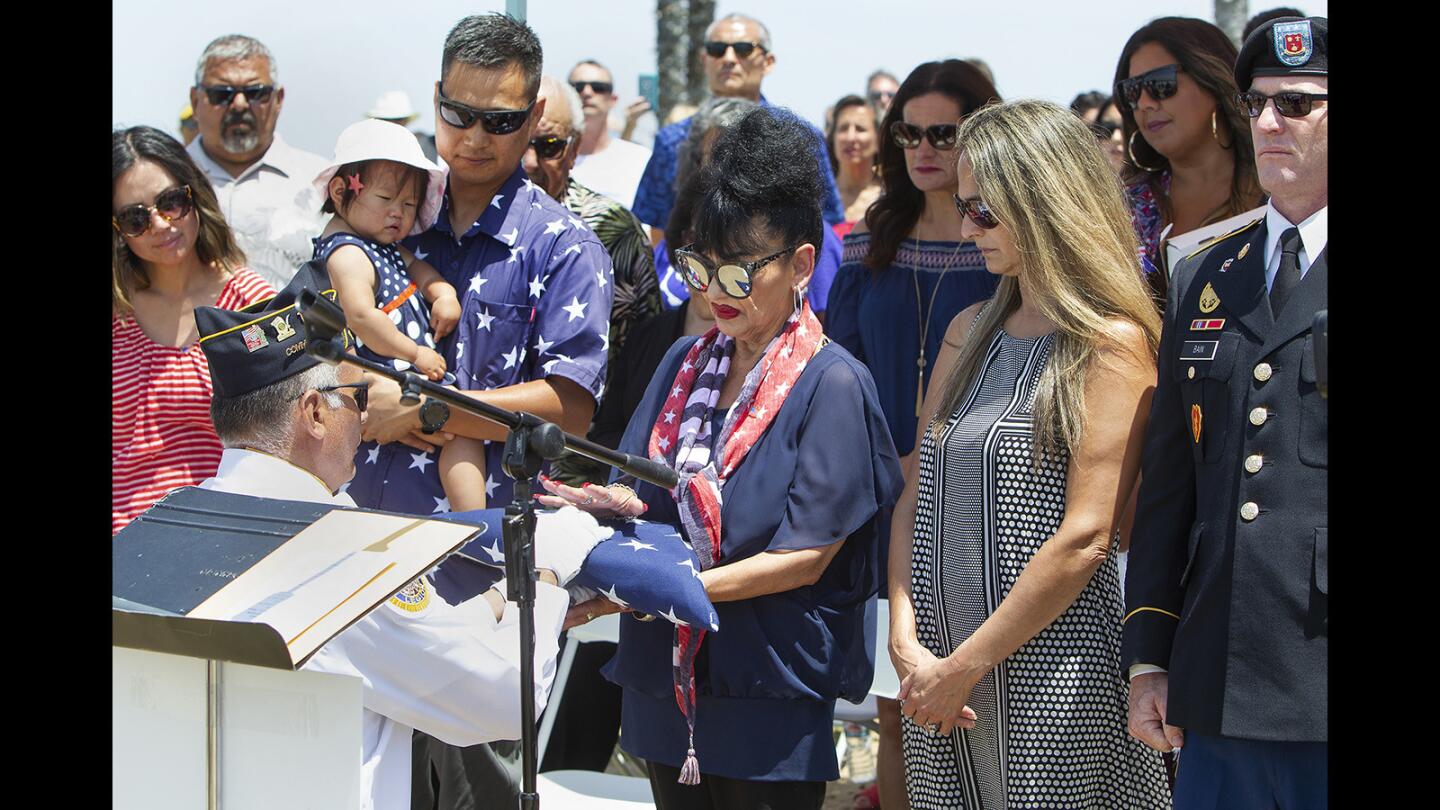 Alberta Martinez, center, Zach Martinez's widow, is given an American flag from Patriot Point in Huntington Beach as she stands among family and friends during a memorial service Monday celebrating her husband's life. Zach Martinez, who died last month, was a Vietnam veteran who raised the flag on a bluff along Pacific Coast Highway near Goldenwest Street on Memorial Day 2010 and created Patriot Point to honor military veterans and their families.