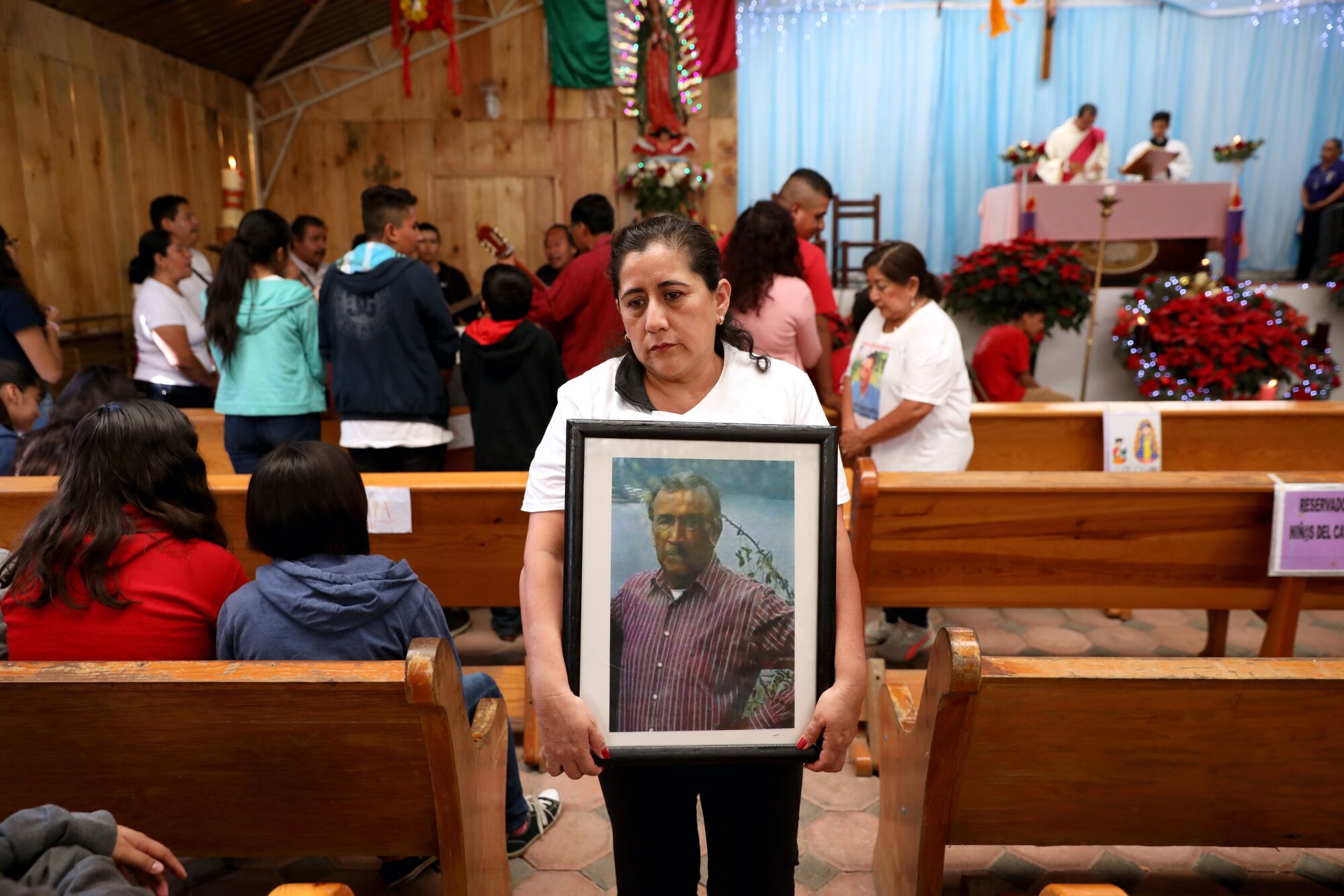 Georgina Quiroz Peñaloza carries a photo of her father, Albino Quiroz Sandoval, after a Mass at Parroquia Nuestra Señora de la Natividad on Dec. 15 in Tepoztlán, Mexico.