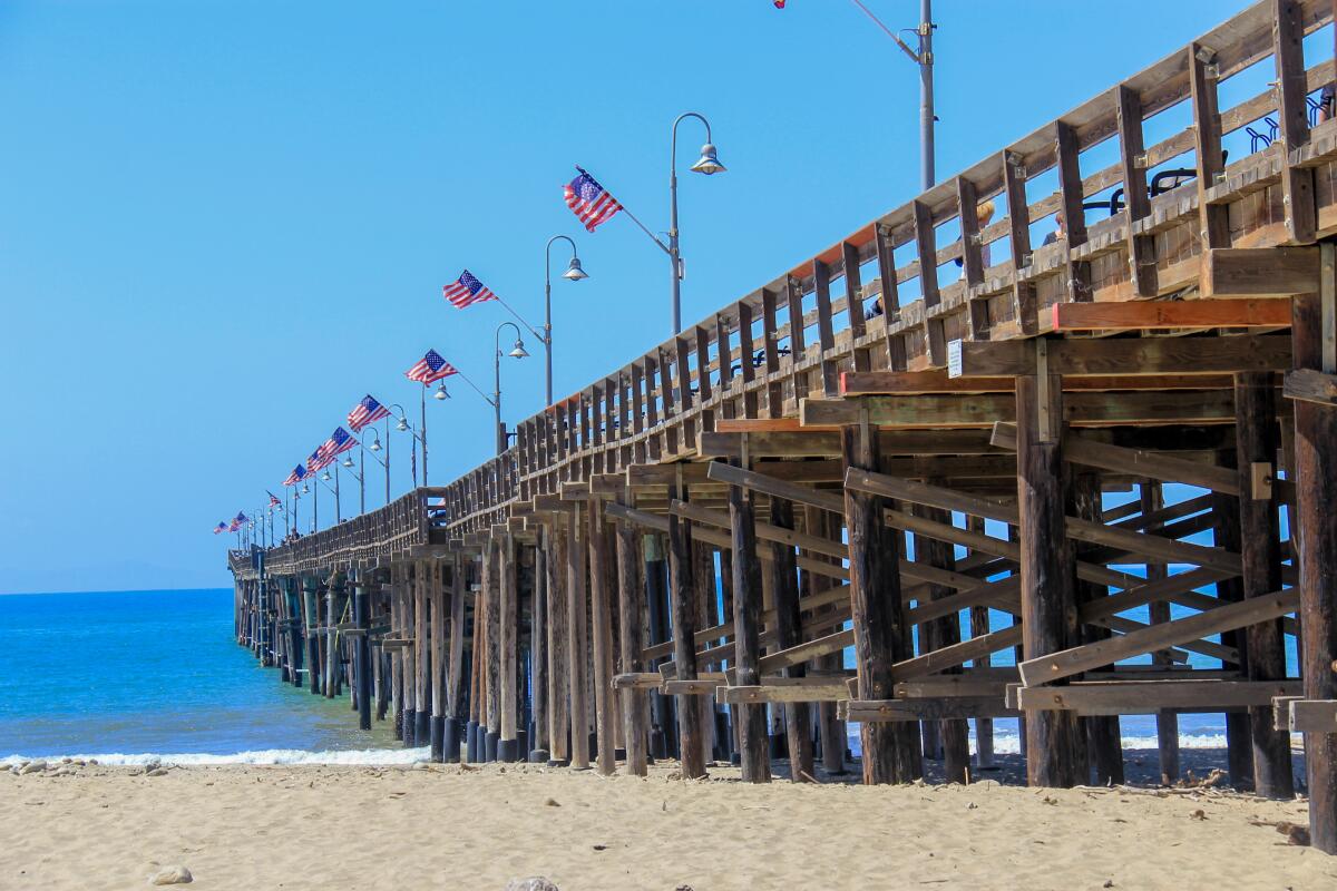 A view from the sand shows the wooden Ventura Pier on a clear, sunny day.