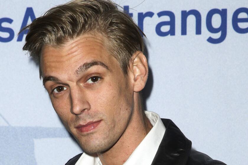 A man with blond hair posing in a white shirt and black jacket