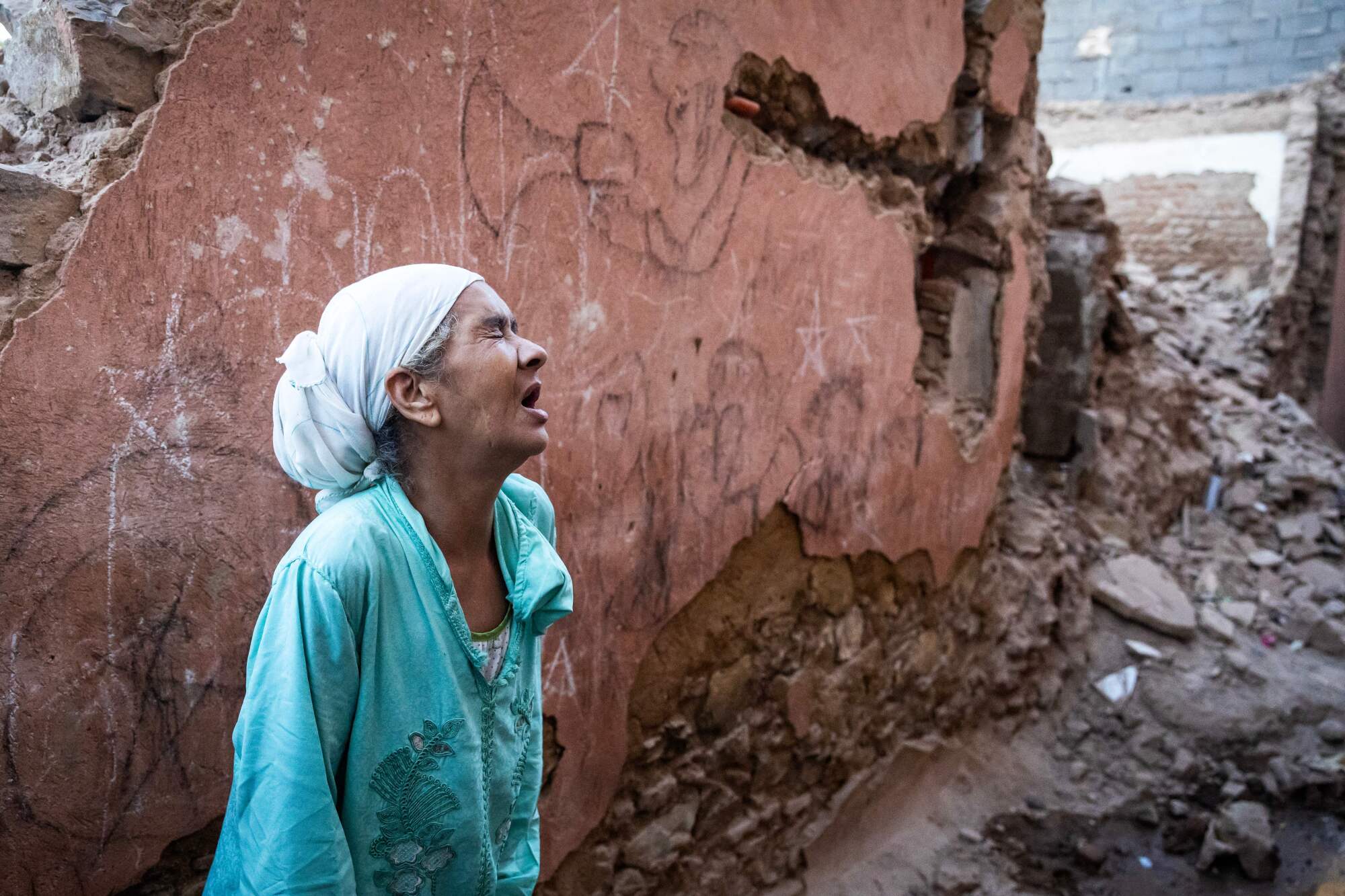 A woman reacts standing in front of her earthquake-damaged house in the old city 