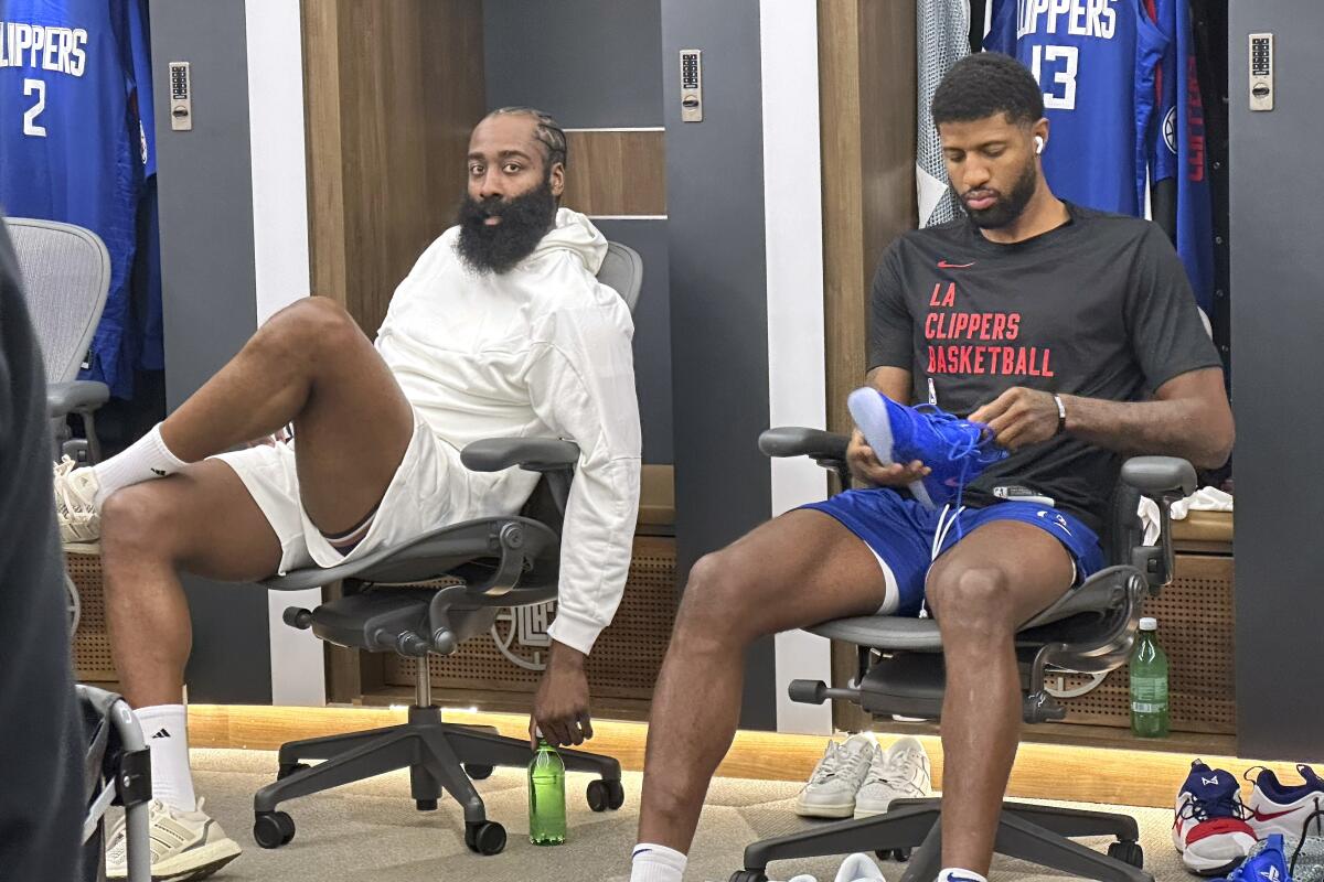 James Harden sits next to new Clippers teammate Paul George in the locker room.