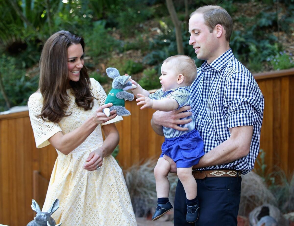 Prince William, Duke of Cambridge, holds Prince George of Cambridge as Catherine, Duchess of Cambridge, gives him a toy bilby during a visit to the Bilby Enclosure at Taronga Zoo in Sydney, Australia.