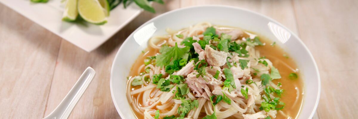 A bowl of quick chicken pho topped with shredded chicken, green onions and fresh cilantro. 