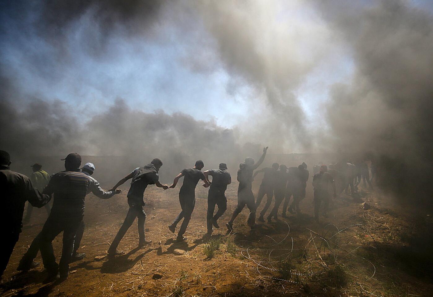 Manifestantes palestinos tratan de tirar el alambre instalado por el ejército israelí a lo largo de la frontera con Israel, en el este de Gaza; hay al menos 58 muertos, siete de ellos menores, y más de 2,700 heridos...