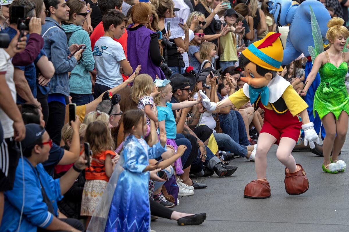 Costumed characters interact with a sitting and standing crowd