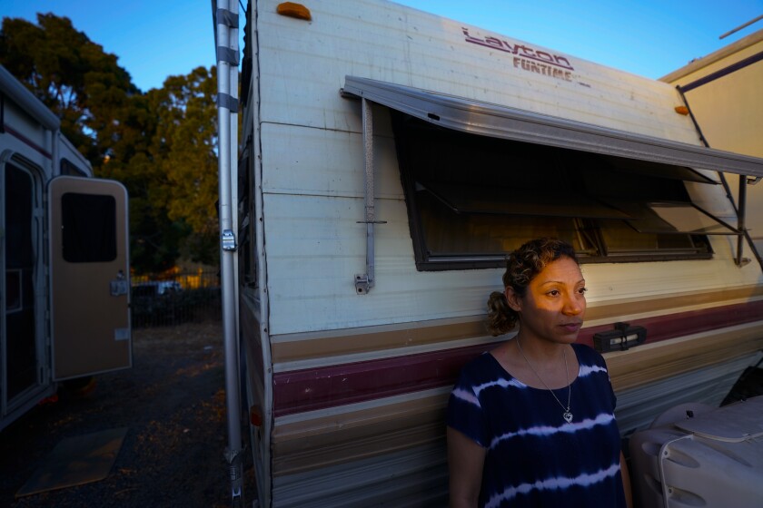A woman stands in the sunlight in front of an RV.