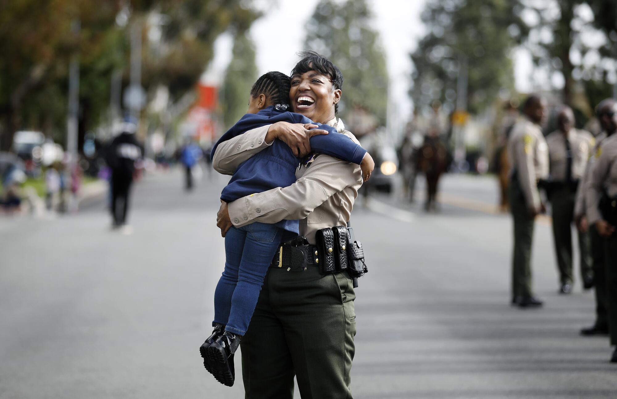 April Tardy with the Los Angeles County Sheriff's Department gets a hug from 3-year-old paradegoer Illy.