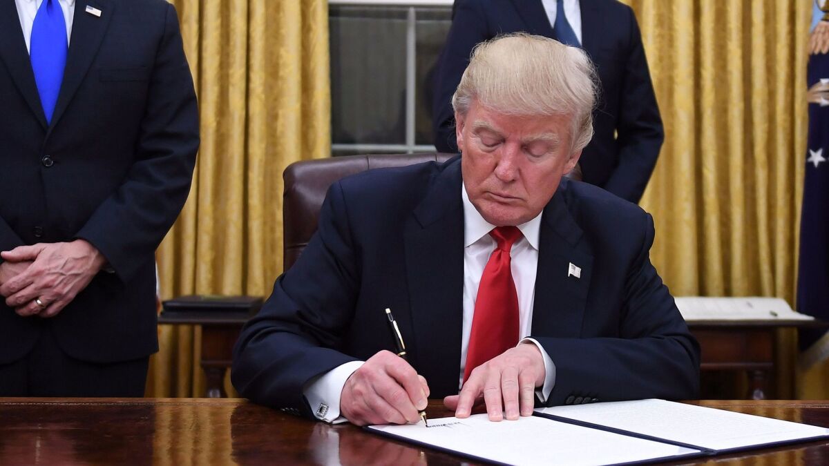 President Donald Trump signing his executive order undermining the Affordable Care Act on Jan. 20.
