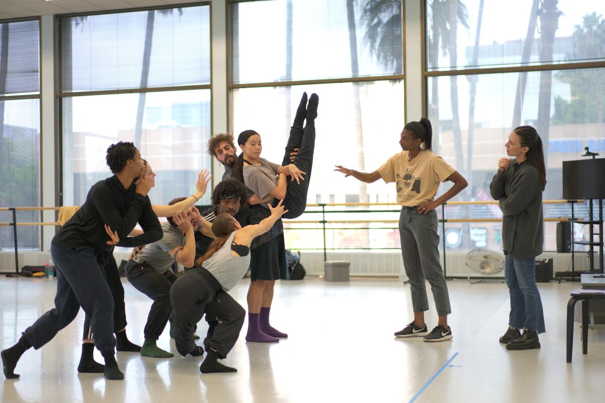 Dancers work in a rehearsal studio with a choreographer.