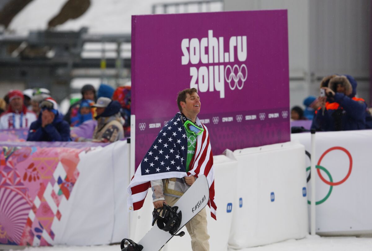 FILE - Bronze medalist Alex Deibold of the United States walks to a flower ceremony after the men's snowboard cross final at the Rosa Khutor Extreme Park, at the 2014 Winter Olympics, Feb. 18, 2014, in Krasnaya Polyana, Russia. Deibold suffered a head injury in a crash during qualifying at a World Cup event just days before his arrival in China. His absence hit his teammates’ hard. (AP Photo/Sergei Grits, File)