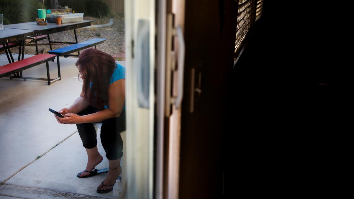 A client of Azalea Springs transitional home takes a cigarette break in the backyard in Hesperia, Calif.