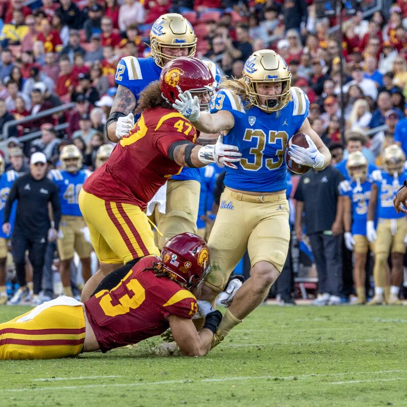 UCLA running back Carson Steele breaks free from tackle attempts by USC's Stanley Ta'ufo'ou and Mason Cobb.