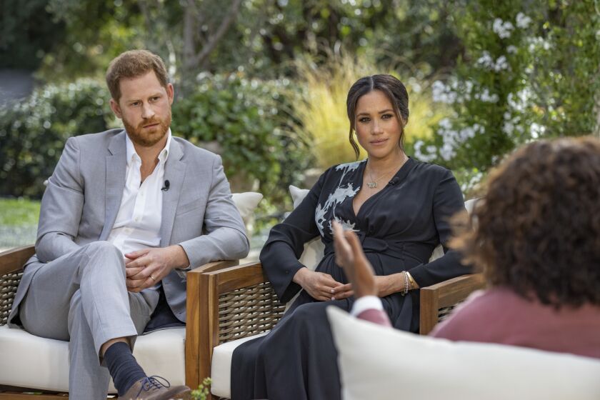 Prince Harry and Meghan Markle sit outside with Oprah Winfrey.