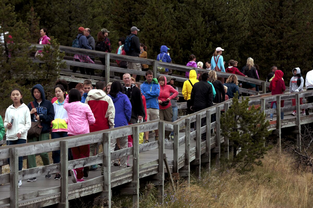 Crowds of visitors cram the wooden walkways around the Midway Geyser Basin leading to the Grand Prismatic Spring and the Excelsior Geyser in Yellowstone National Park.