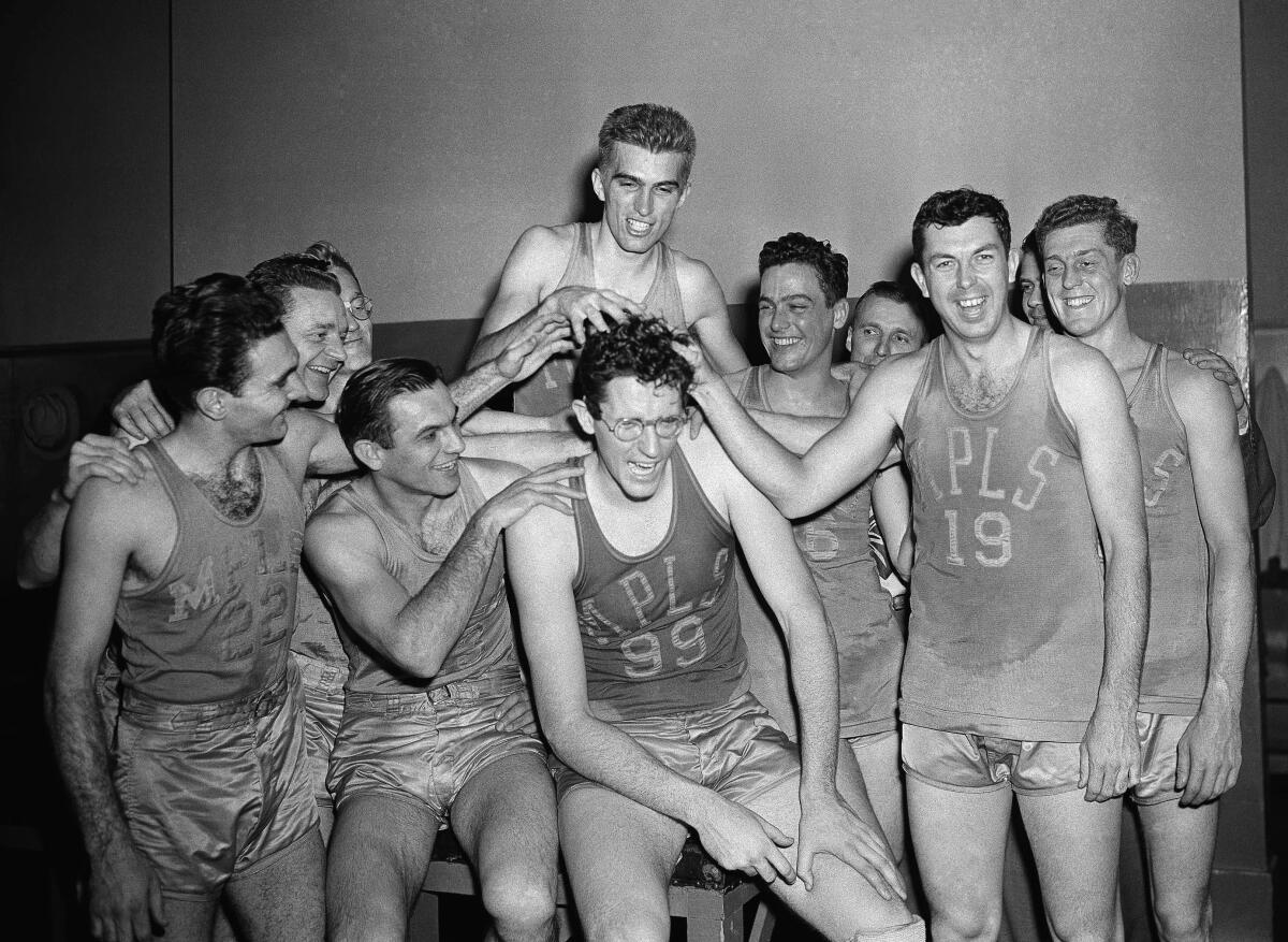 George Mikan (No. 99, wearing glasses), Minneapolis center, gets his hair mussed by teammates.