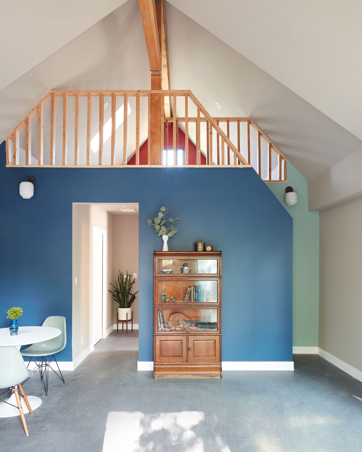 A blue wall with a bookshelf against it and a loft above 