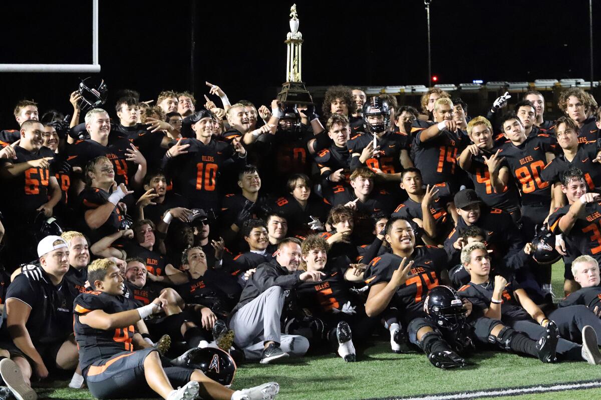 The Huntington Beach football team poses for a picture with the Victory Trophy after winning the Oil vs. Water rivalry game.