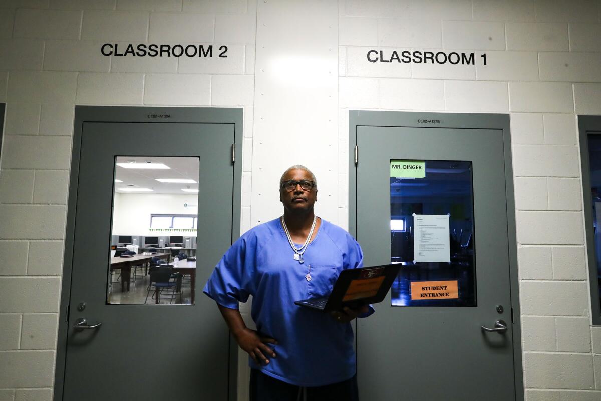Luke Scott stands in between two doors labeled Classroom 1 and Classroom 2 at Mule Creek State Prison. 