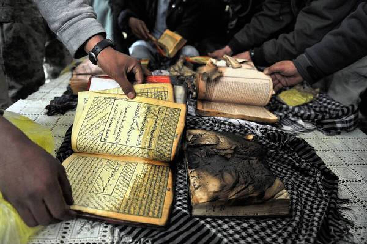 A demonstrator shows a damaged Koran during a protest in February at the gate of Bagram air base north of Kabul in Afghanistan.
