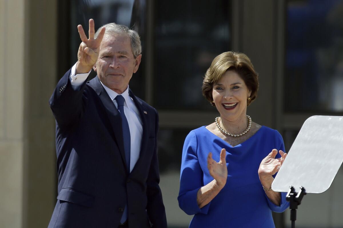 Former President George W. Bush, accompanied by his wife former first lady Laura Bush, flashes the "W" sign after his speech during the dedication of the George W. Bush Presidential Center in Dallas.