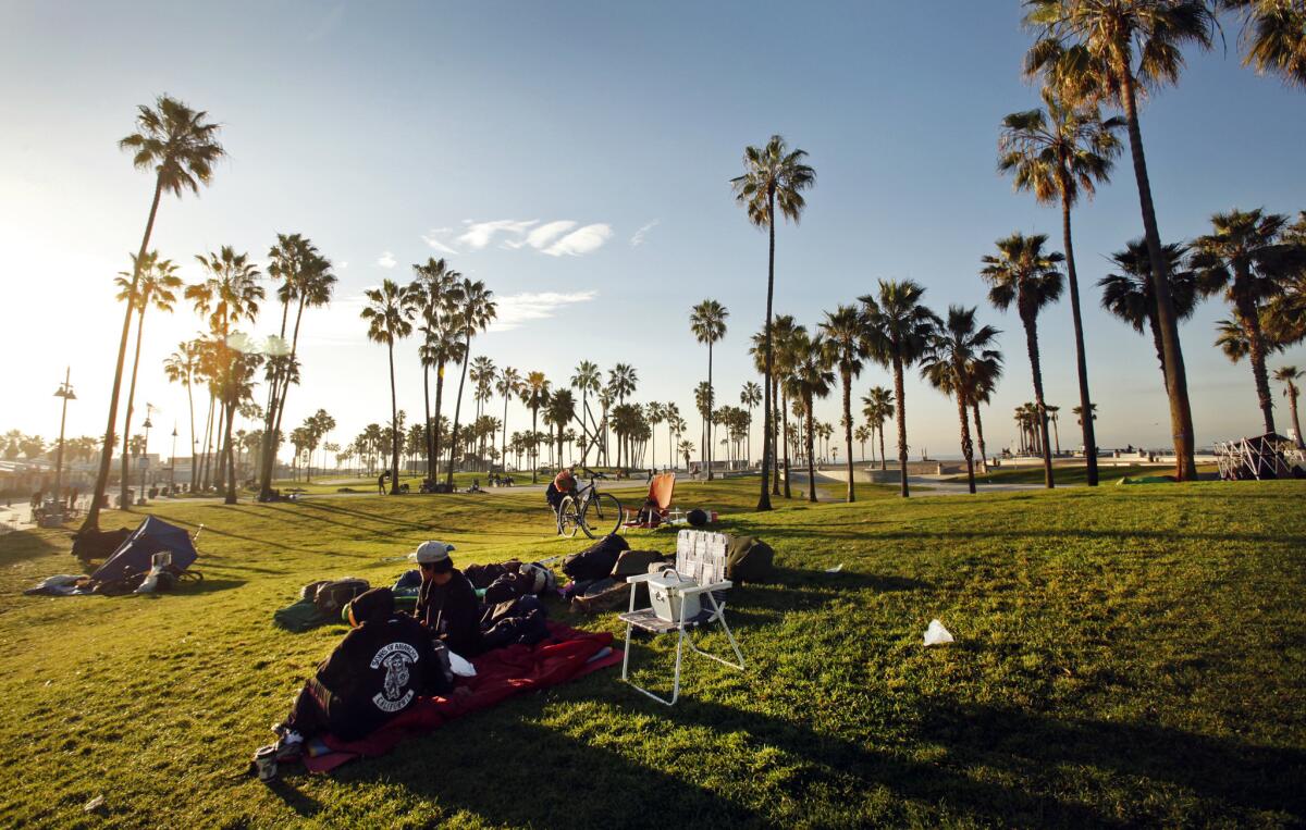 Homeless people rest in the greenbelt along the Venice Boardwalk at sunrise last month.