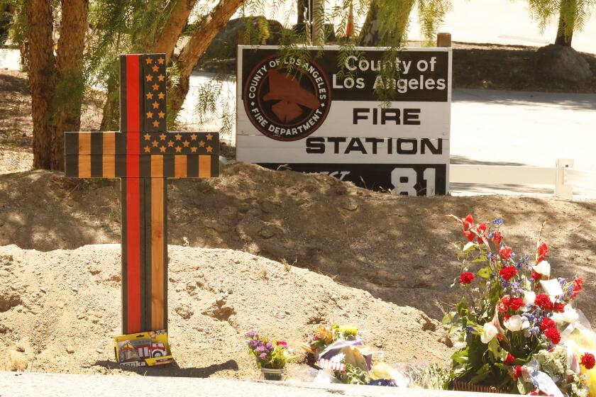 AGUA DULCE, CA - JUNE 04: A memorial features a cross made of wood along with flowers outside Los Angeles County Fire Dept. Station 81 at 8710 Sierra Hwy in Agua Dulce where LA County Firefighter specialist Tory Carlon, 44, was killed in a shooting last Tuesday. The twenty-year veteran of the department was killed by fellow off-duty firefighter Jonathan Tatone, who opened fire wounding a Captain as well, then fled to his home in nearby Acton, barricaded himself inside, and set the house on fire before he was found dead. LA County Fire Station 81 on Friday, June 4, 2021 in Agua Dulce, CA. (Al Seib / Los Angeles Times).