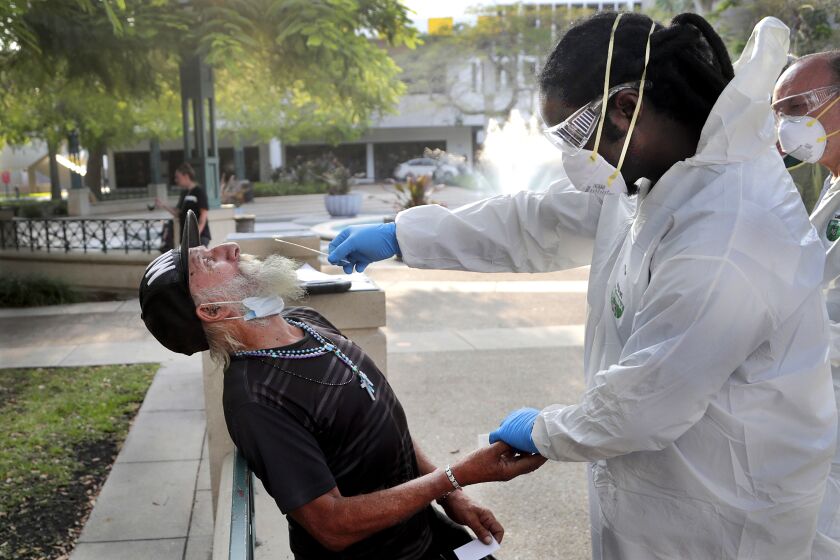 FLORIDA, USA: Nurse practitioner Gregory Pierre, right, holds the hand of Leonardo Toledo Martinez, who is homeless, as he is tested for COVID-19 in a program administered by the Miami-Dade County Homeless Trust during the new coronavirus pandemic in Miami.