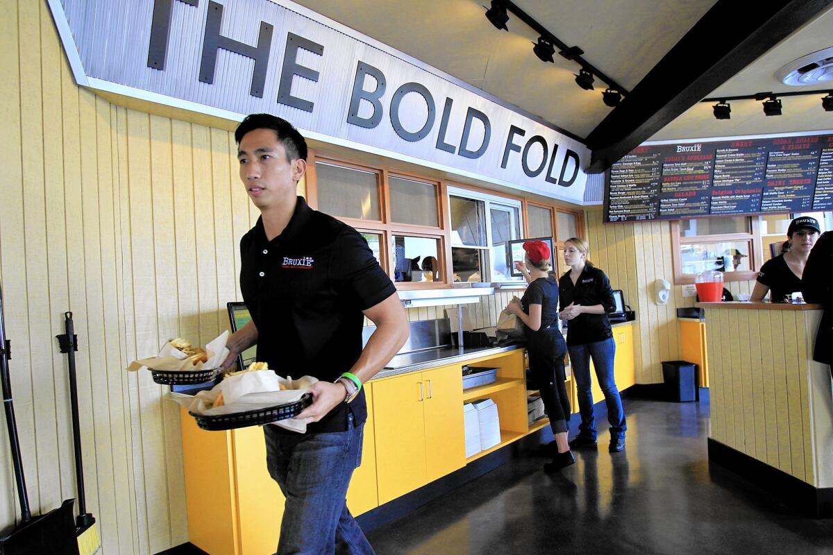 Employees fill orders during Bruxie's opening in Costa Mesa in November 2013. The waffle sandwich shop closed Wednesday, with its workers being relocated to the chain's restaurants in Irvine and Huntington Beach.