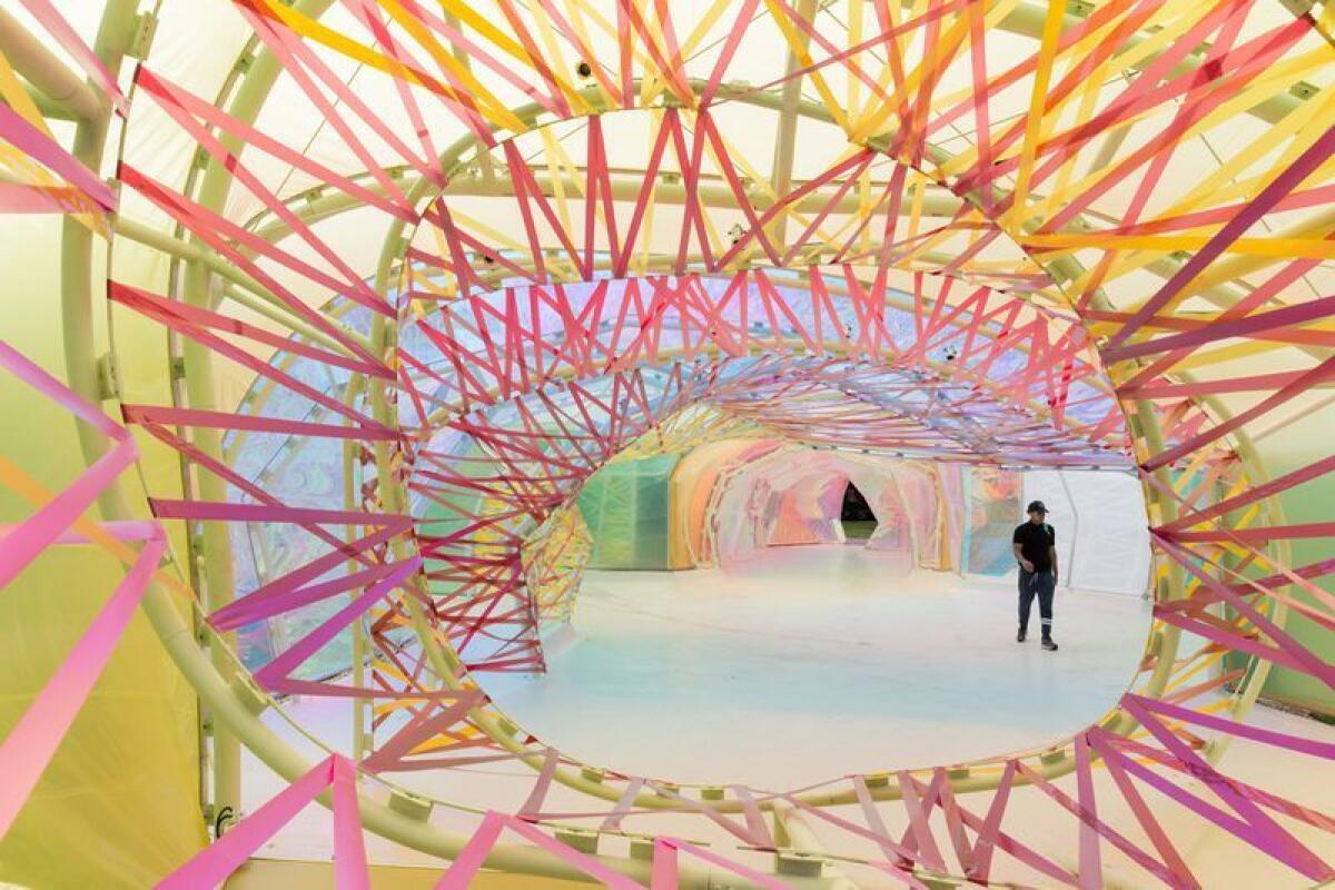 A view through pink ribbons to a structure sheathed in translucent polymer.