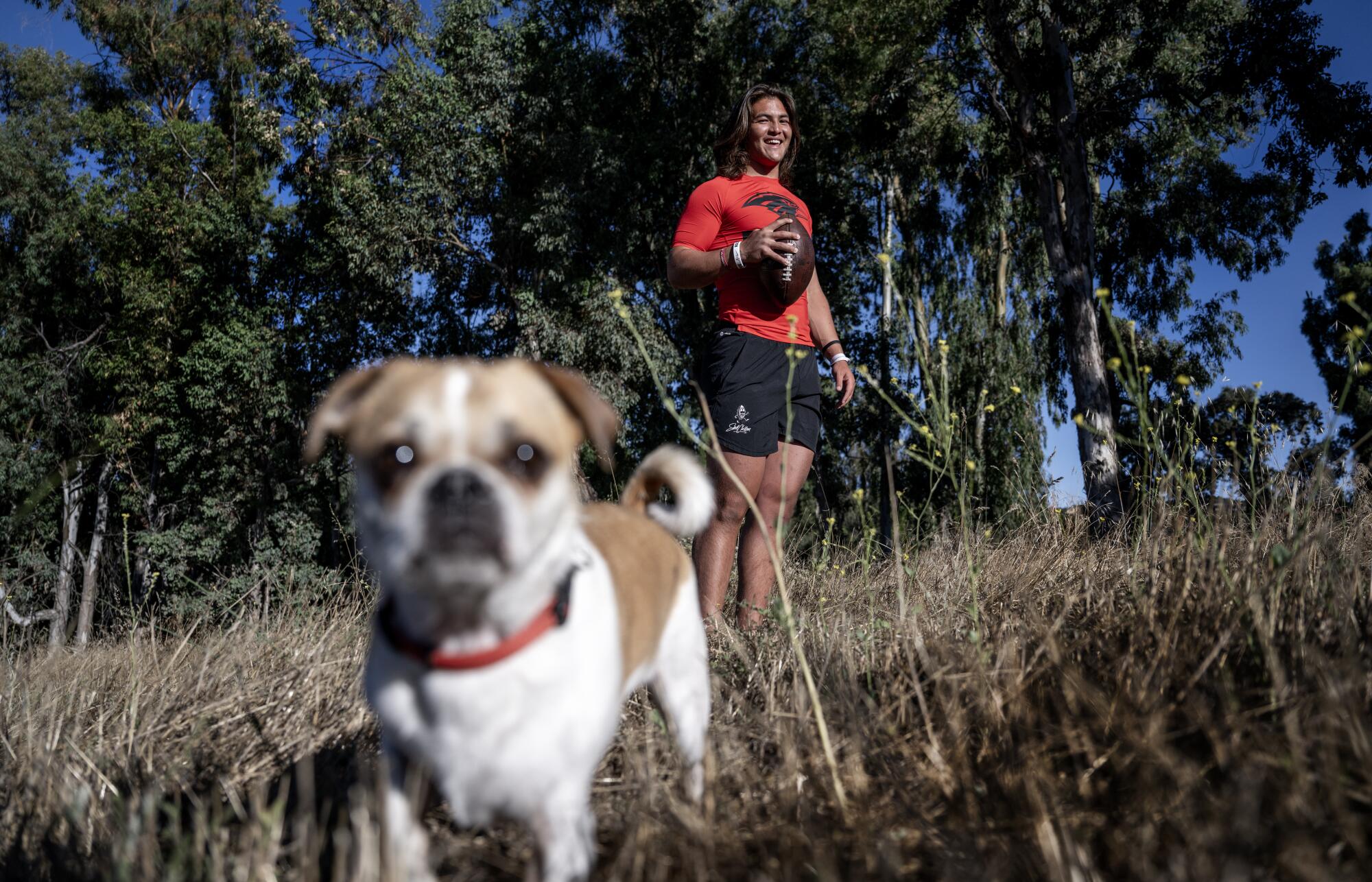 Murrieta Valley junior quarterback Bear Bachmeier with his dog in the rural landscape at his home.