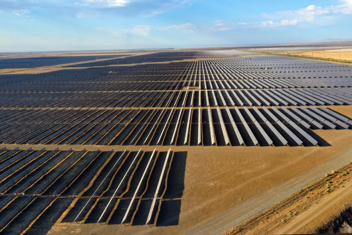 Solar panels stretch into the distance on a flat plain.