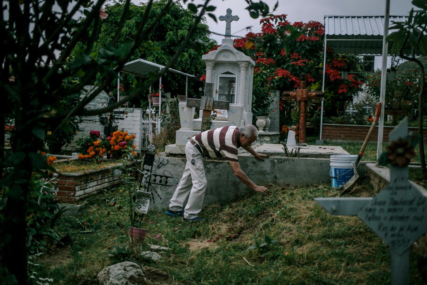 Ricardo Soto Olivar, 65, tends to the grave of his mother and father in Metepec, Puebla. It is customary to clean graves the night or day before Day of the Dead. During the September earthquake, Soto and his wife sustained about $6,000 worth of damage to the home they spent their whole lives together building.