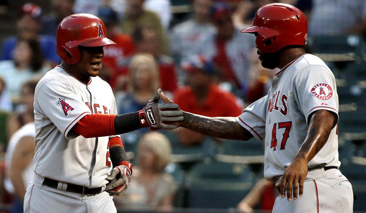 Angels shortstop Erick Aybar, left, is congratulated by second baseman Howie Kendrick (47) after hitting a two-run home run against the Rangers in the second inning Thursday night.