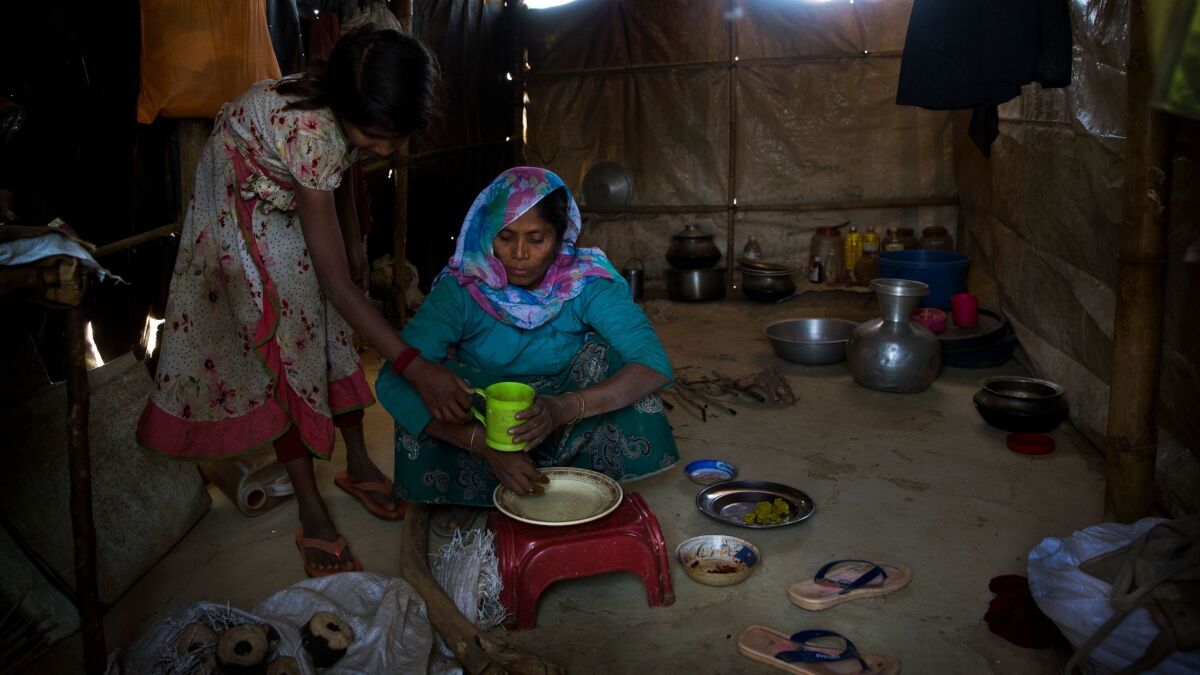 In this Jan. 28, 2018 photo, Rohingya Muslim refugees Nooranksih, 9, left, and her mother Rohima Khatu, 45, originally from the Myanmar village of Gu Dar Pyin, eat inside their makeshift shelter at Balukhali refugee camp, Bangladesh. The Associated Press has confirmed more than five previously unreported mass graves in the Myanmar village of Gu Dar Pyin through multiple interviews with more than two dozen survivors in Bangladesh refugee camps and through time-stamped cellphone videos. "There were dead bodies everywhere, bones and body parts, all decomposing, so I couldn't tell which one was my husband," Khatu said. "I was weeping while I was there. I was crying loudly, 'Where did you go? Where did you go?'". (AP Photo/Manish Swarup)