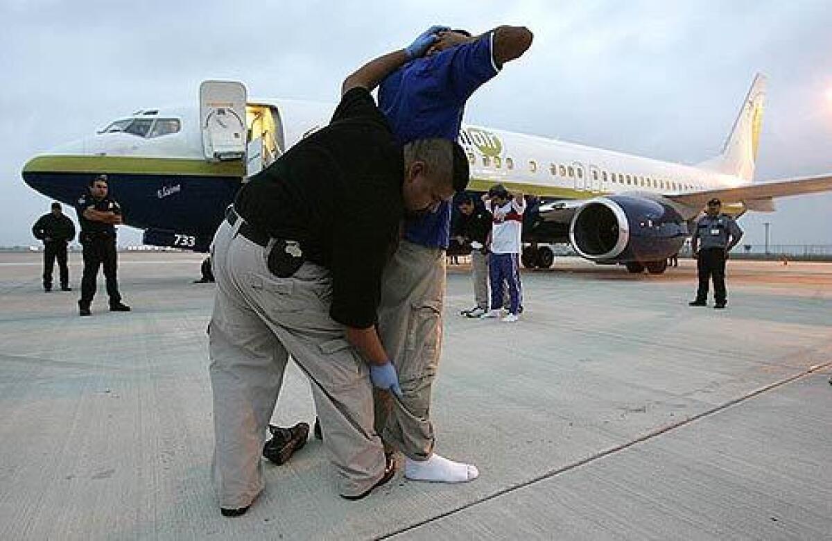 Immigration and Customs Enforcement agents search undocumented immigrants before placing them aboard a plane that will take them back to El Salvador.