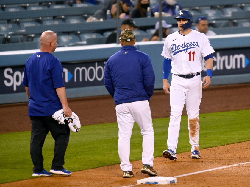 Dodgers outfielder AJ Pollock tests his hamstring in front of Dodgers manager Dave Roberts and a team trainer.