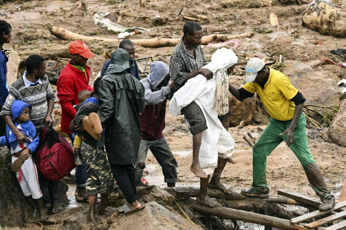 An injured man helped accrossin Blantyre, Malawi, Monday, March 13, 2023. The unrelenting Cyclone Freddy that is currently battering southern Africa has killed more than 50 people in Malawi and Mozambique since it struck the continent for a second time on Saturday night, (AP Photo/Thoko Chikondi)