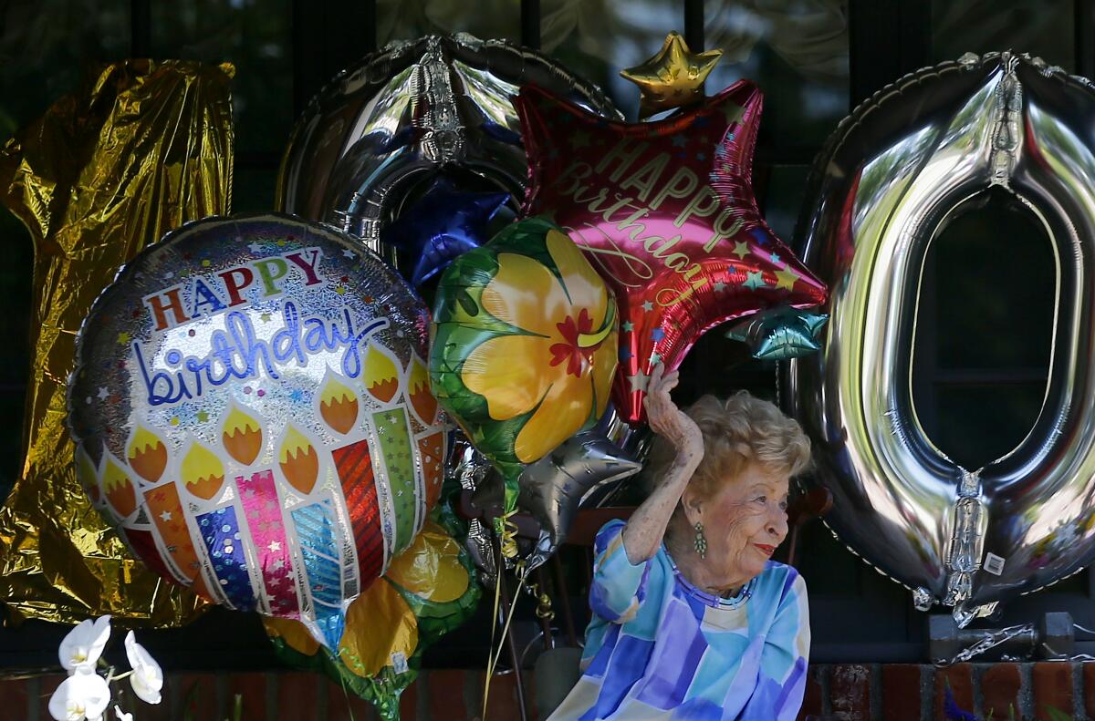 Joan Bayley waves to a drive-by parade of relatives and friends celebrating her 100th birthday.