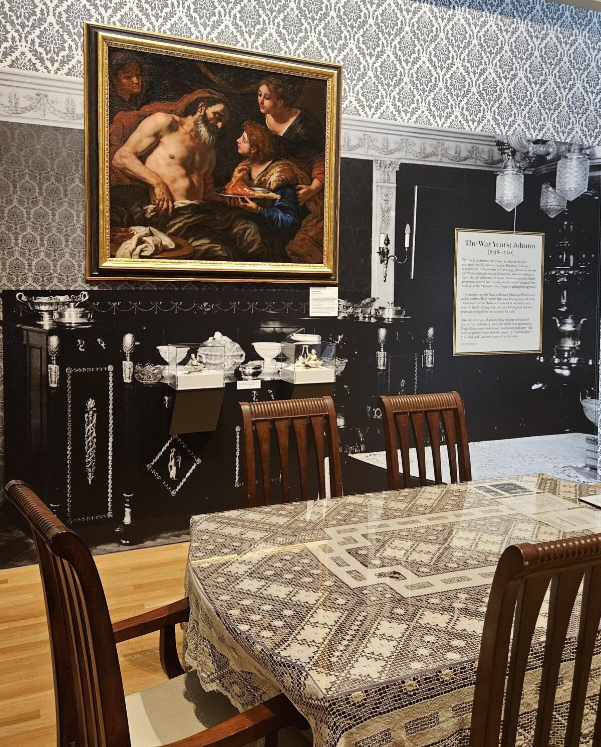 A museum gallery is designed to resemble a family dining room, where a baroque painting by Carl Loth hangs on a wall.