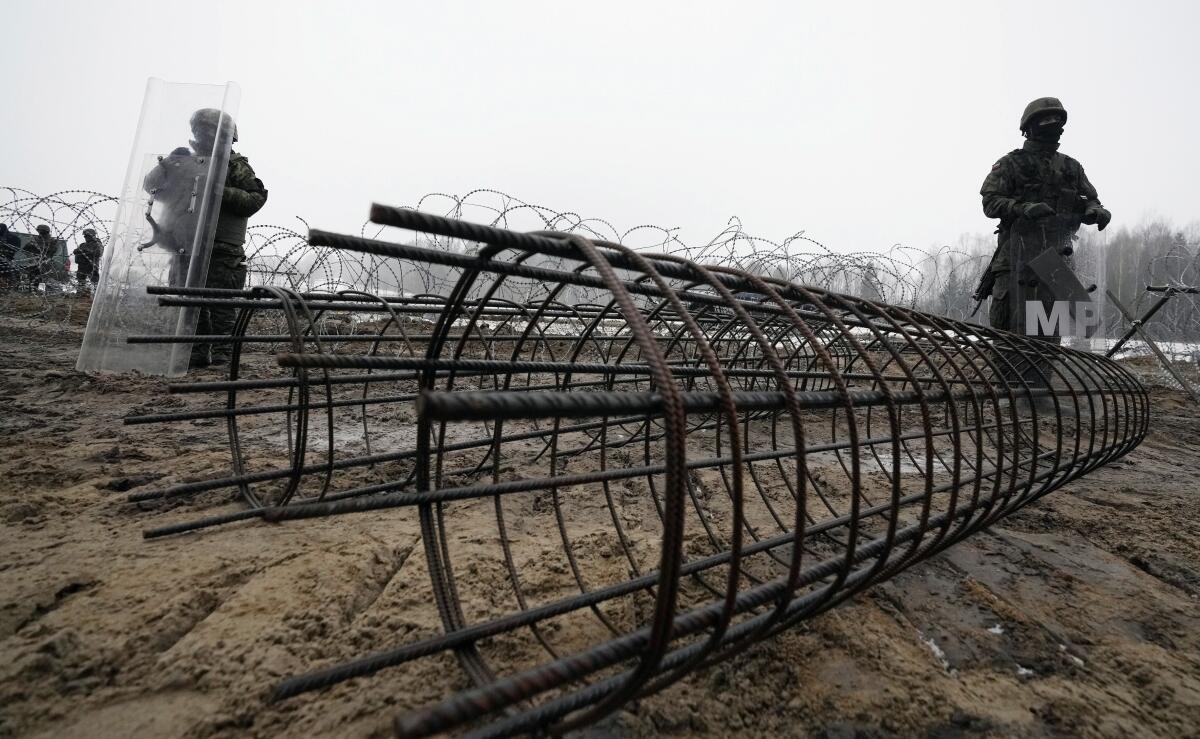 Servicemen standing among building materials for border barrier