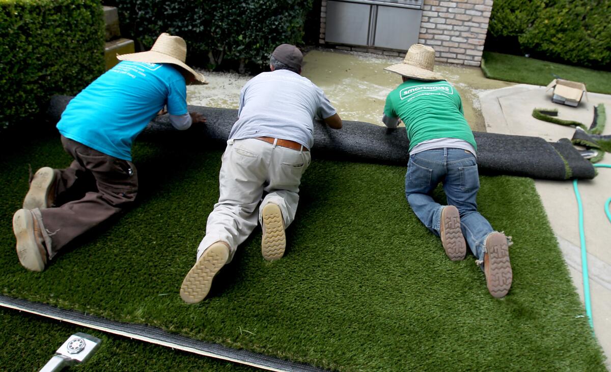 A crew from Smartgrass Synthetic Turf installs artificial grass in the backyard of a home in Pacific Palisades.