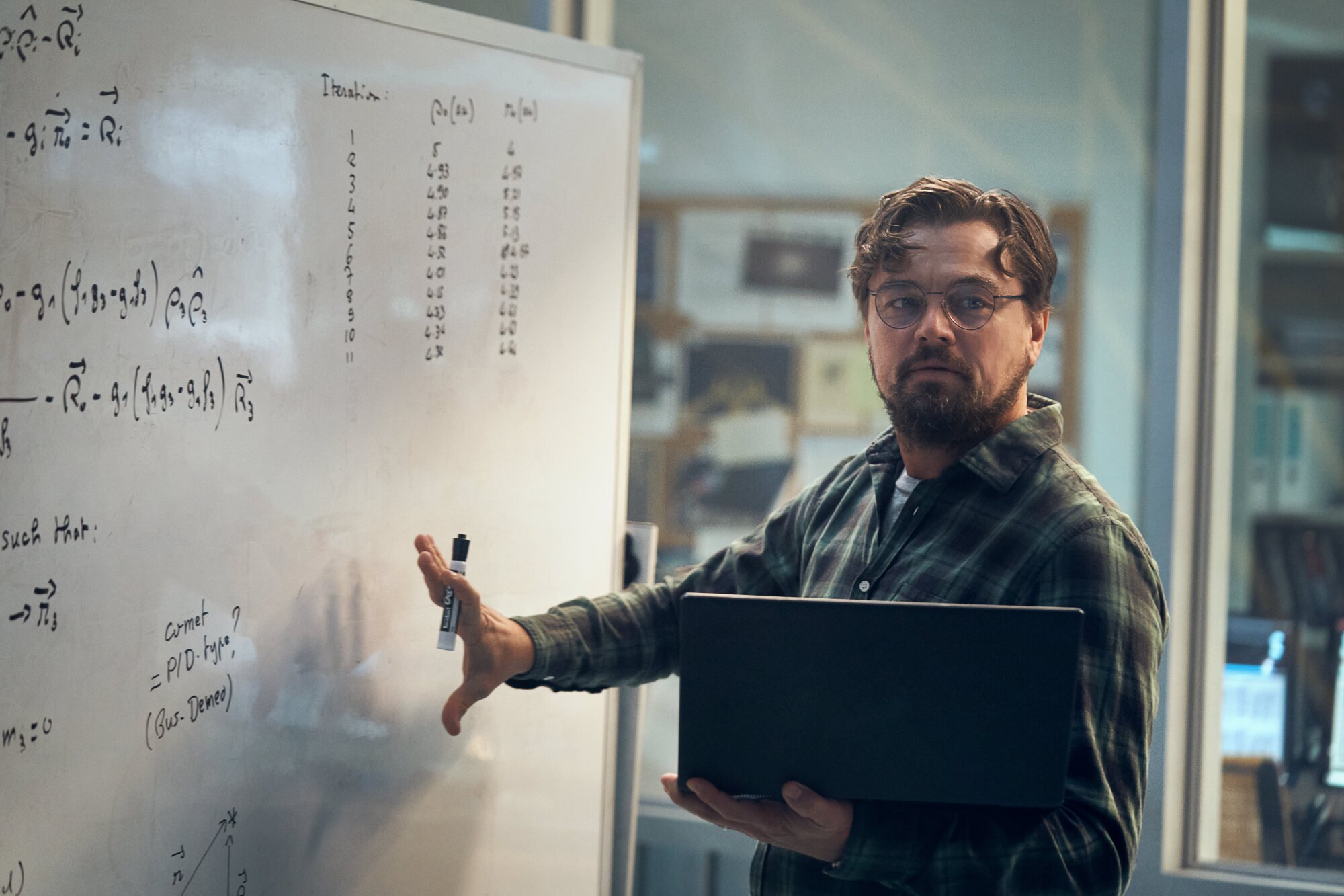 LEONARDO DICAPRIO as DR. RANDALL MINDY, holding a laptop in front of a whiteboard.