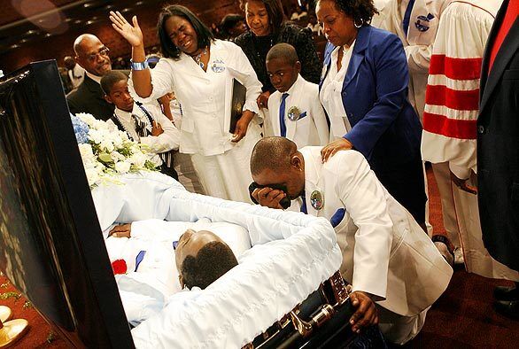 Anita Shaw prays as her husband Jamiel Shaw Sr., kneels at the casket of their son Jamiel Shaw Jr.