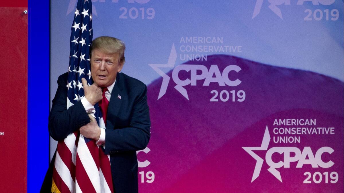 President Trump hugs a U.S. flag as he arrives to speak at the Conservative Political Action Conference on March 2, 2019.