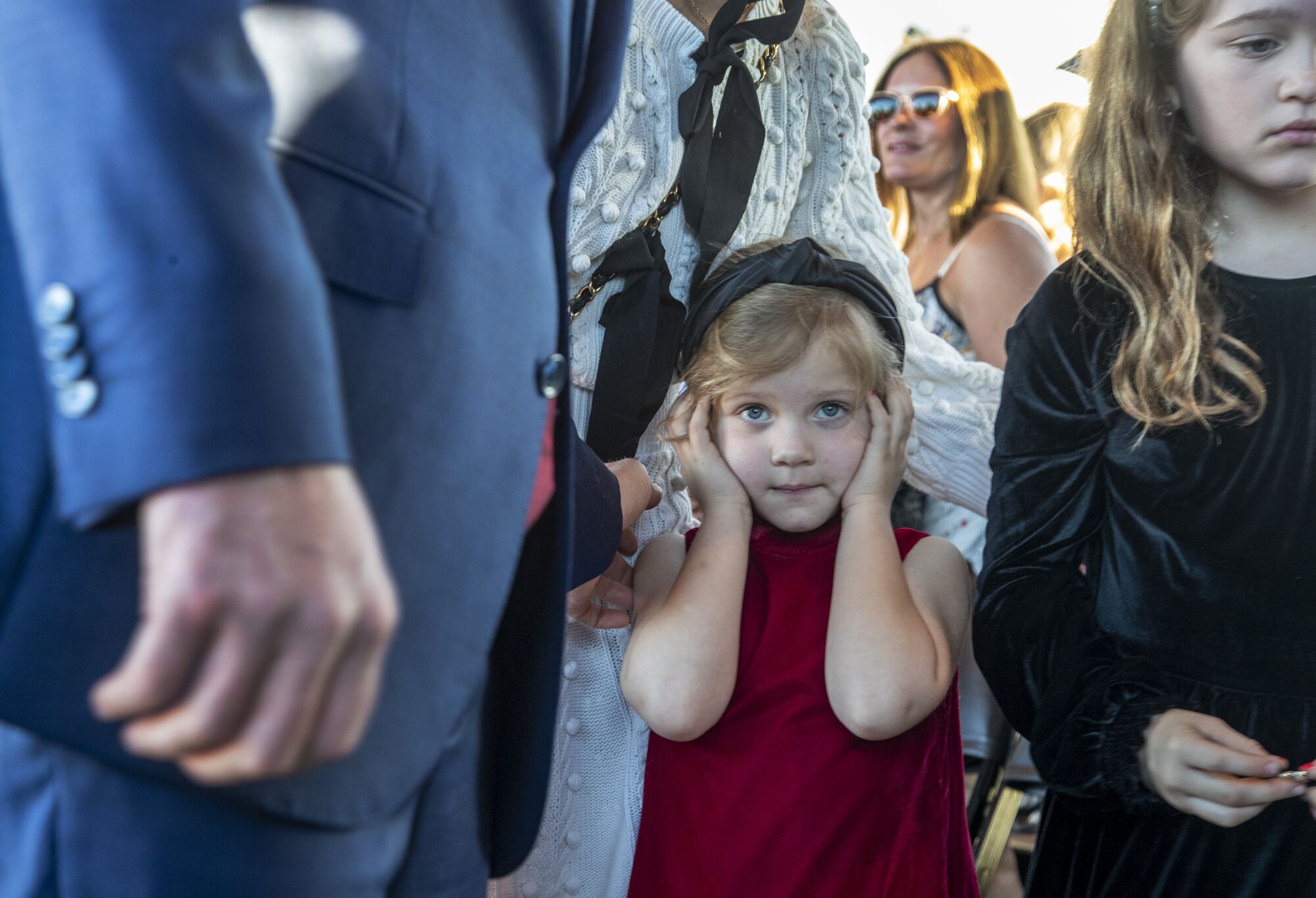Lincoln Riley's youngest daughter, Stella, plugs her ears as Trojan band plays.
