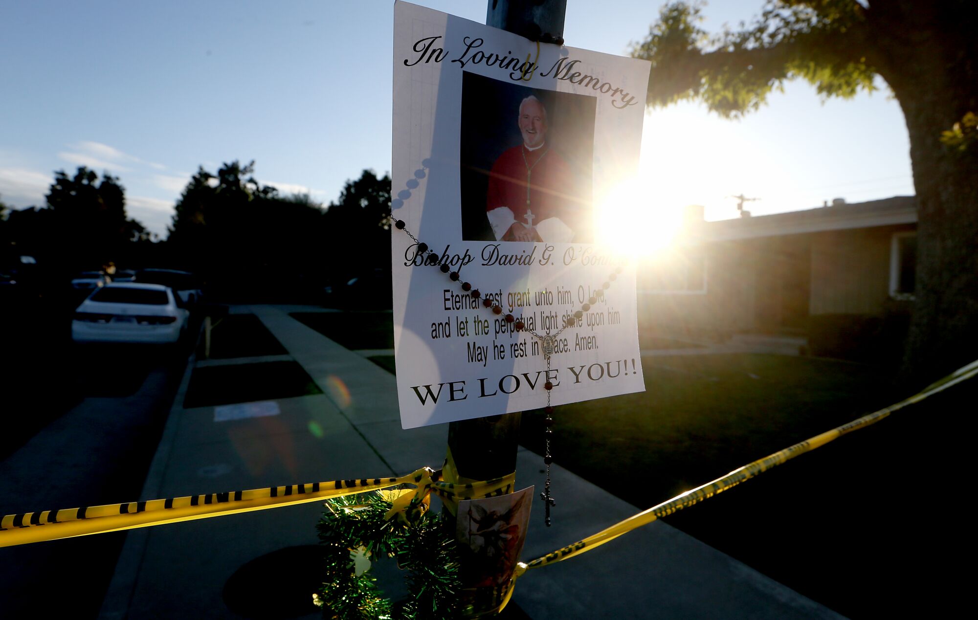 A picture of. Roman Catholic Bishop David O'Connell and police tape hang on a street sign 